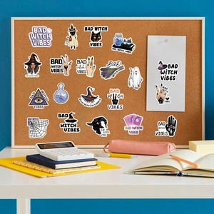 Detail of waterproof Bad Witch Vibes stickers featuring mystical motifs on a cork board