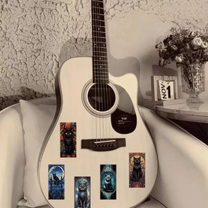 Dettaglio di adesivi goth con gatti neri applicati su una chitarra acustica bianca