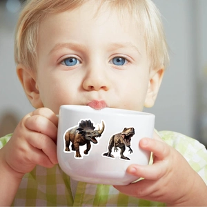 Bébé tenant un mug en céramique blanc orné d'autocollants dinosaures réalistes