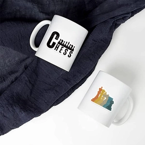 Détail de deux mugs en céramique blanche avec silhouettes d'échecs sur fond de tissu bleu