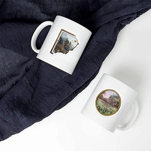 Detail of white ceramic mugs featuring vintage artistic landscape patterns on fabric