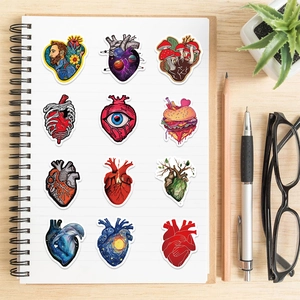 Artistic anatomical heart stickers with surreal designs displayed on a notebook