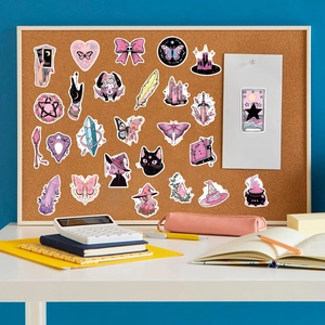 Detailed view of pink and green witch graffiti stickers on a corkboard setup