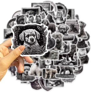 Close-up of hand holding black and white hand-drawn dog stickers for laptop and guitar