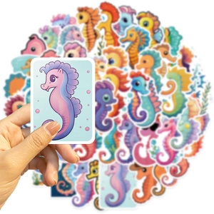 Gros plan d'une main tenant un autocollant d'hippocampe rose imperméable et coloré