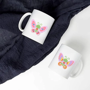 Close-up of a white ceramic mug featuring a colorful butterfly illustration and round handle