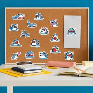 Detailed view of blue cartoon shark stickers arranged on a cork board with stationery