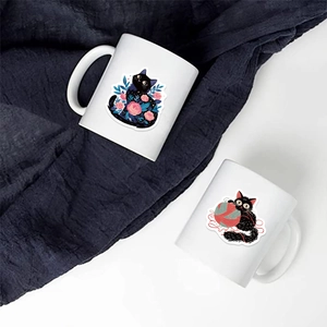 Détail de mugs en céramique blanche avec illustrations de chats noirs et fleurs