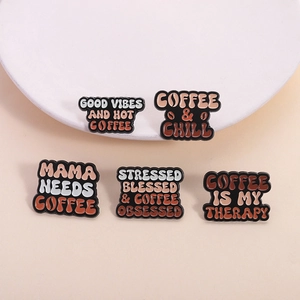 Cinco pines de café esmaltados con frases motivadoras presentados sobre un fondo rosa suave