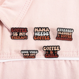 Detalle de pines de café esmaltados en tela rosa con eslóganes Coffee is my therapy