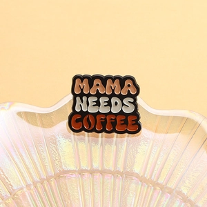 Pin de esmalte con texto MAMA NEEDS COFFEE e icono de grano de café en fondo negro