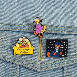 Cartoon detective enamel duck brooches set displayed on blue denim jacket fabric