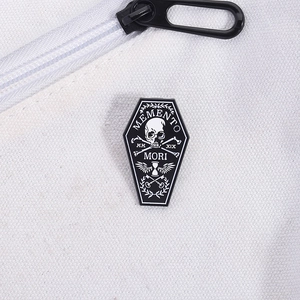 Macro shot of Memento Mori gothic coffin enamel pin with skull motif on white canvas