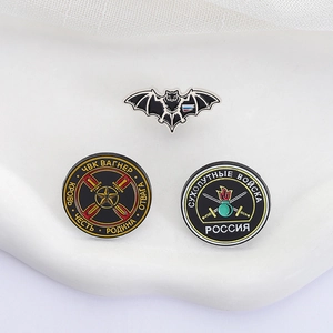 Macro detail of military enamel pins set featuring bat and Wagner shield on white background