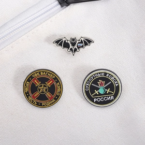 Detail of three military enamel pins featuring bat and shield designs on canvas