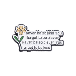 Macro shot of an enamel pin featuring floral motifs and motivational quotes for readers