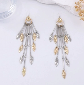 Détail macro de boucles d'oreilles pompons avec pendentifs feuilles martelées bicolores