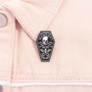 Close-up of gothic coffin enamel pin with skull and Memento Mori on denim jacket