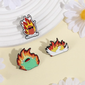 Detailansicht kreativer Emaille-Pins mit Flammen-Frosch und Gans auf Dekoplatte