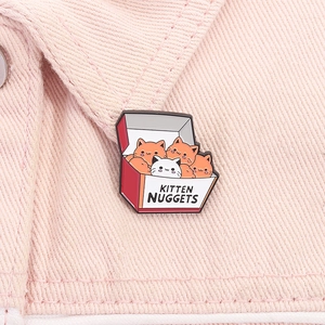 Dettaglio macro della spilla smaltata kitten nuggets su tessuto denim rosa