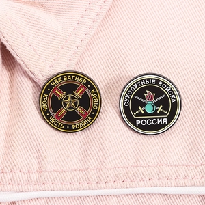 Macro view of military enamel pins with Russian Wagner and Army emblems on denim fabric