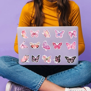 Waterdichte vlinder stickers in zachte pastelkleuren op een paarse laptop oppervlak