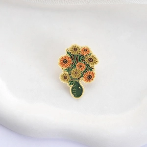 Artistic sunflower enamel pin in a green vase shown on a minimalist white ceramic tray
