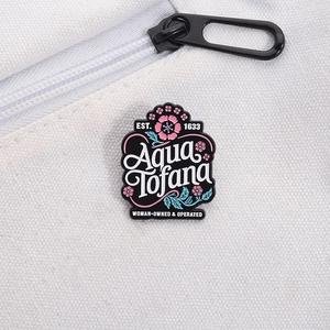 Detail of Aqua Tofana enamel pin with pink cherry blossoms on white canvas bag