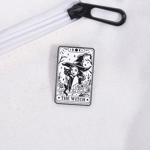 Detail of The Witch tarot black cat enamel pin pinned on a white canvas bag