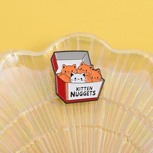Dettaglio della graziosa spilla smaltata cat nuggets su un vassoio a conchiglia