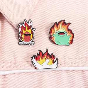 Detaillierte Ansicht von drei Emaille-Pins mit Kartoffel, Frosch und Gans auf rosa Denim