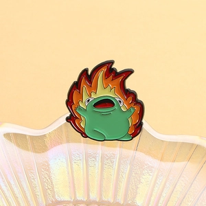 Detail der grünen Emaille-Anstecknadel Frosch mit roten Flammen auf einer Schale