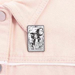 Detail of The Witch tarot enamel pin with black cat on pink denim jacket fabric