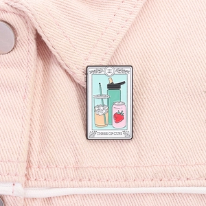 Close-up of Three of Cups tarot enamel pin on pink denim showing coffee and drinks