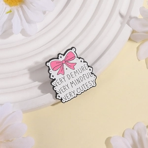 Pink ribbon bow enamel pin with 'Very Demure, Very Mindful' quote on display tray