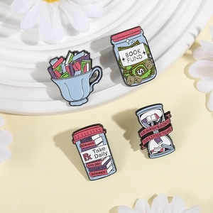 Detail of four creative book-themed enamel pins featuring a cup, jar, and hourglass