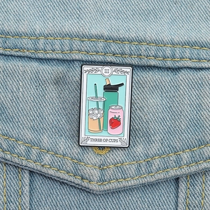 Three of Cups tarot enamel pin featuring beverage motifs on a denim jacket pocket
