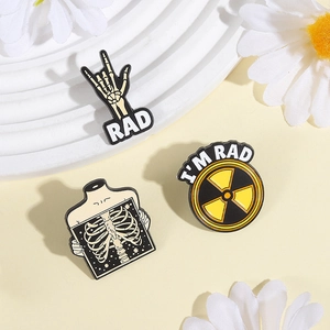 Lot de trois pin's en émail avec main squelettique et logo de radiation sur socle