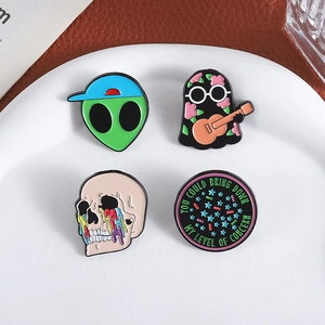 Detailed macro view of four enamel lapel pins with alien, ghost and skull motifs on a tray