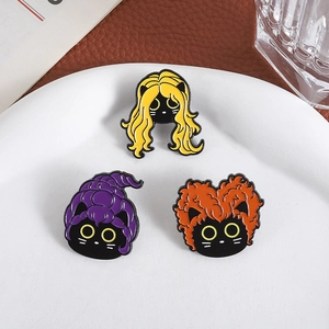 Trois broches en émail chat noir avec coiffures colorées sur une assiette blanche