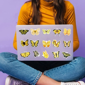 Detail van decoratieve gele vlinderstickers op een lavendelkleurige laptop voor DIY