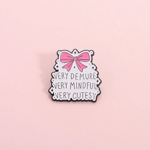 Enamel pin with pink bow and Very Demure Very Cutesy text on pink background
