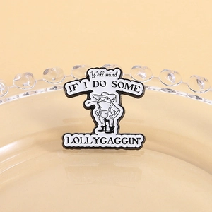 Detail of cowboy frog enamel pin with humor quote on a decorative glass plate