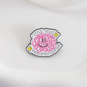 Detail of pink wool ball enamel pin with smiley and Little Miss Procrastinator text