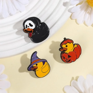 Three Halloween enamel pins featuring yellow ducks in witch, pumpkin, and ghost costumes