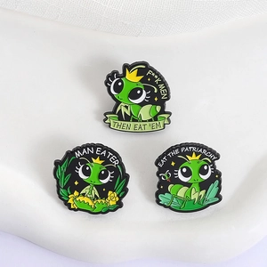 Cute green mantis enamel pins with yellow crowns on a minimalist white ceramic stand