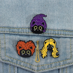Trois pin's de sorcières avec visages de chat noir sur une veste en jean bleue