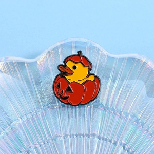 Detail shot of a cute enamel yellow duck wearing a pumpkin costume on a glass tray