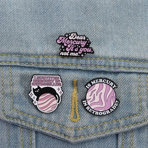 Lot de trois pin's émaillés violets avec chat et espace sur une veste en jean
