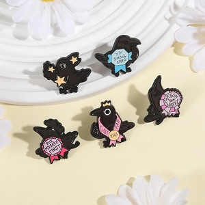 Macro detail of five black crow enamel pins with colorful motivational quotes on a display